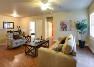 Living room with tan couch, brown coffee table, and hardwood floors at Stallion Pointe apartments