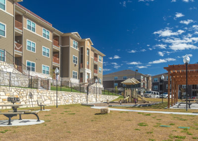 Exterior view of Stallion Pointe apartments with playground and seating area